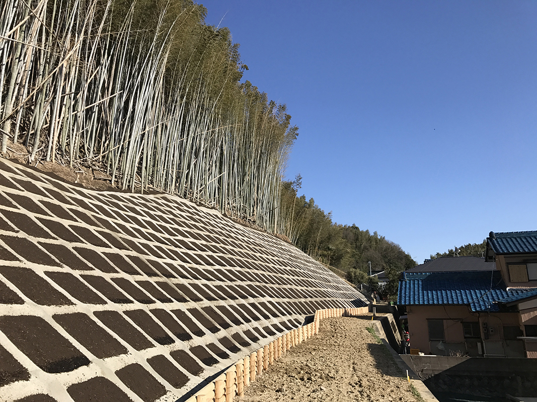 住宅に隣接する斜面に格子状の法面保護を施した土木工事